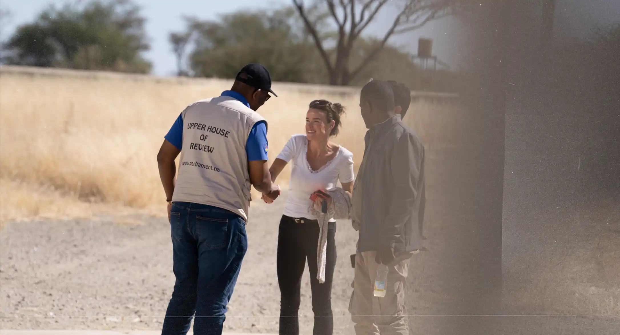 Group of researchers and parliament representatives shaking hands on gravel road in the savanna