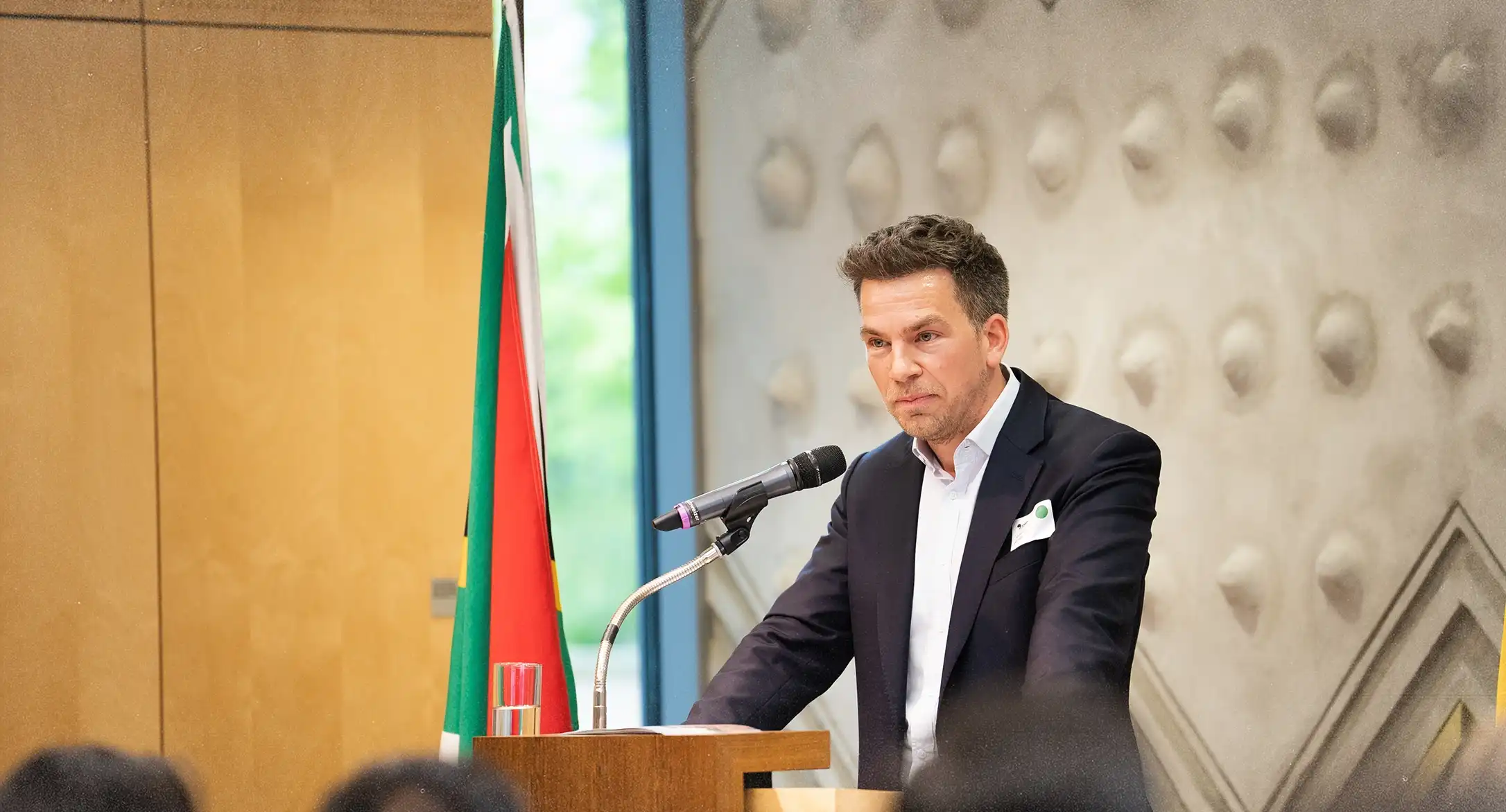 Simon Brunke hält eine Rede auf einem Podium in der südafrikanischen Botschaft